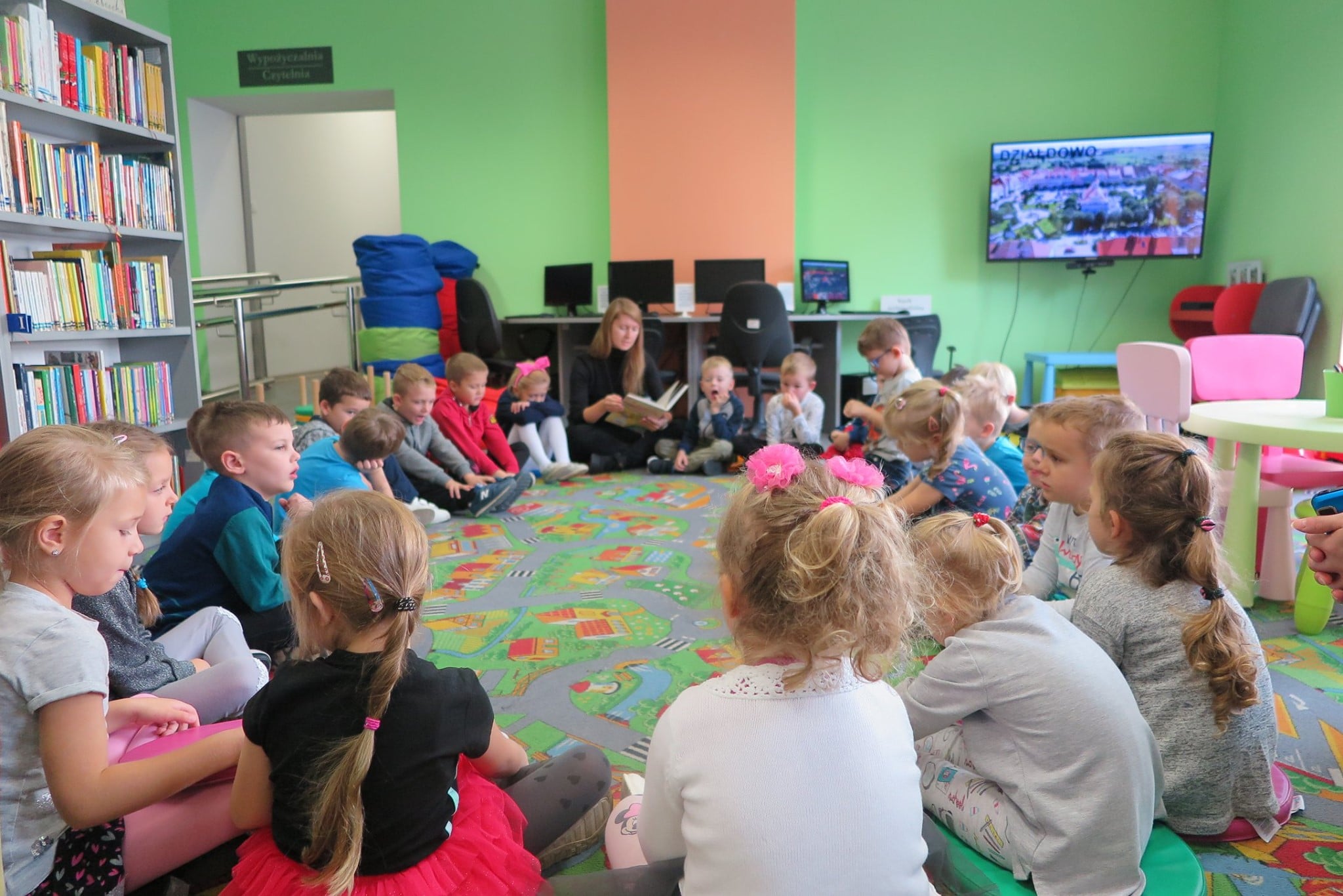Wnętrze biblioteki, oddział dla dzieci. Na pufach siedzą przedszkolaki z grupy ''Jeżyki'' z Przedszkola nr 1.  Zajęcia prowadzi Aleksandra Cybulska.