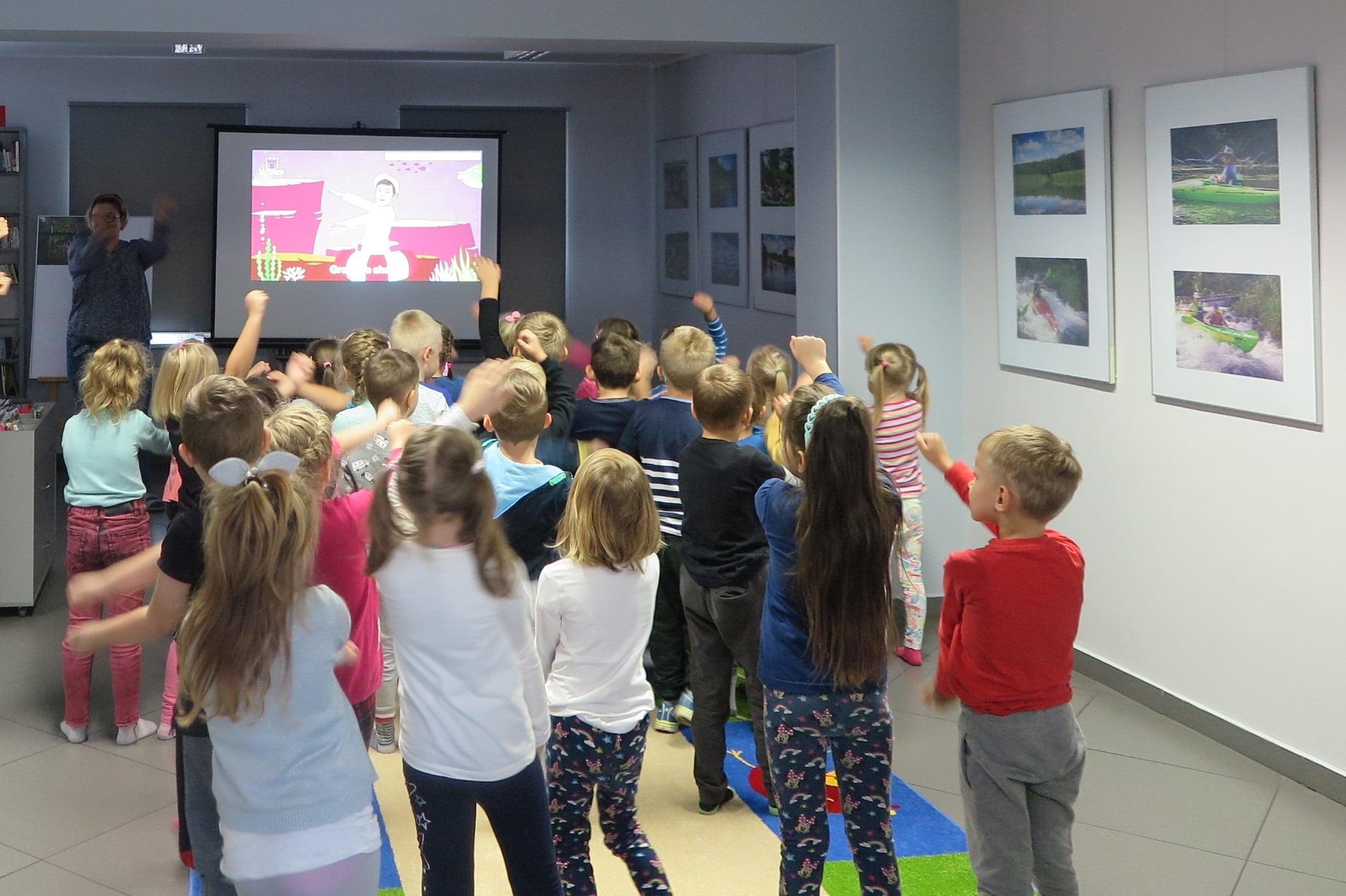 Wnętrze biblioteki, mediateka. Dzieci z przedszkola ''U Misia'' tańczą do piosenki ''Baby shark''. 
