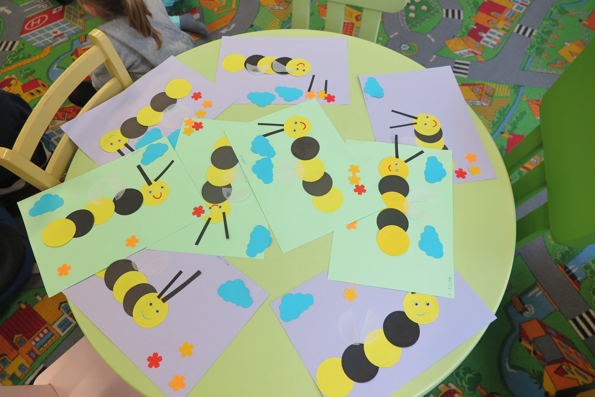 Na stoliku kartki z kolorowymi pszczółkami wykonane przez dzieci. 