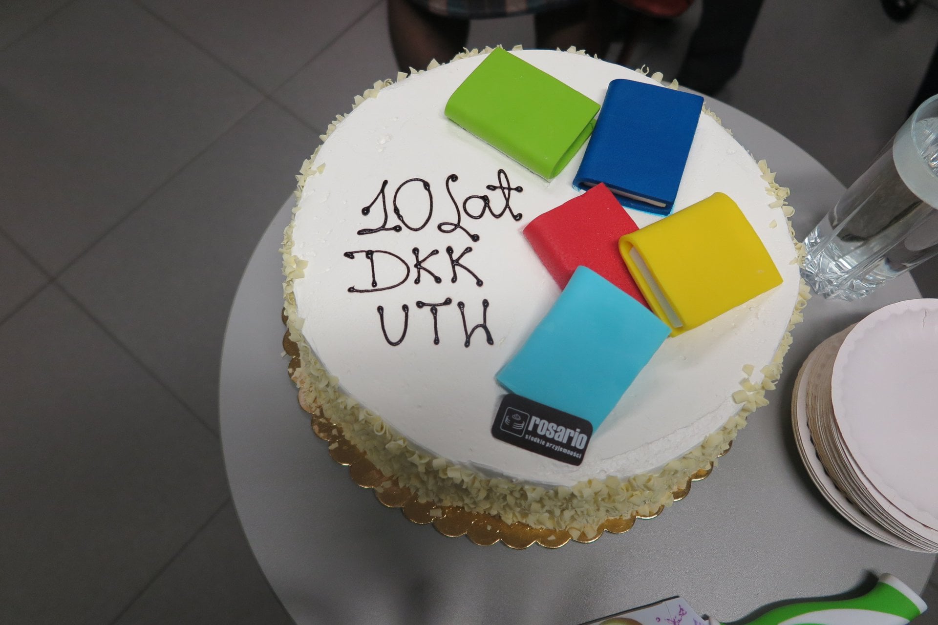 Na stoliku tort z okazji 10LAT działającego klubu DKK UTW , na torcie napis 10lat DKK UTW oraz malutkie marcepanowe książki. 