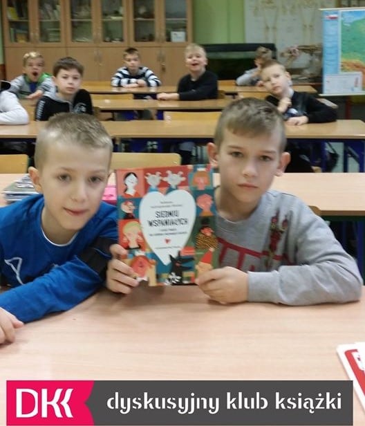Wnętrze klasy w SP nr 1 w Działdowie. DKK omawia książkę ''Siedmiu wspaniałych i sześć innych nie całkiem nieznanych historii'' Roksany Jędrzejewskiej- Wróbel. Dzieci trzymają książkę jeden egzemplarz autorki. 