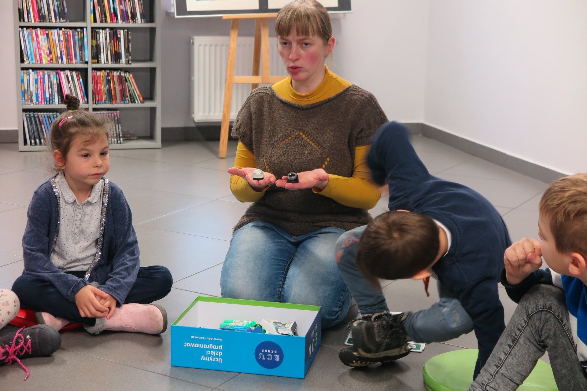 Wnętrze biblioteki,mediateka. Bibliotekarka Małgorzata Trąmpczyńska pokazuje małe ozoboty dzieciom z przedszkola ''U Misia''.