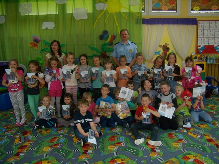 Wnętrze przedszkola, grupa dzieci  z nauczycielką i panem Pawłem Buńkowskim ze Straży Miejskiej.