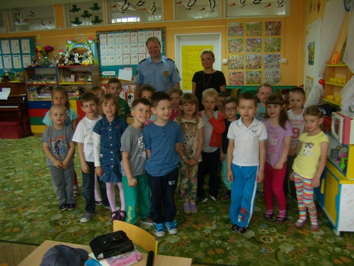 Wnętrze przedszkola, grupa dzieci  z nauczycielką i panem Pawłem Buńkowskim ze Straży Miejskiej.