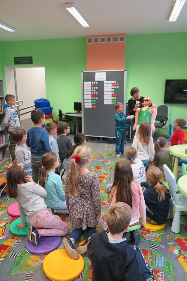 Wnętrze biblioteki, z okazji ferii grupa dzieci bierze udział w ''Fabryce Zimowych Pomysłów w MBP''. Zajęcia prowadzi bibliotekarka Ania Wiśniewska. 