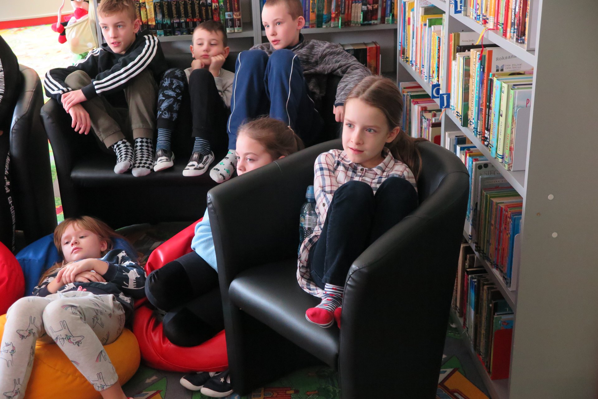 Wnętrze biblioteki,dzieci oglądają bajkę disneya.