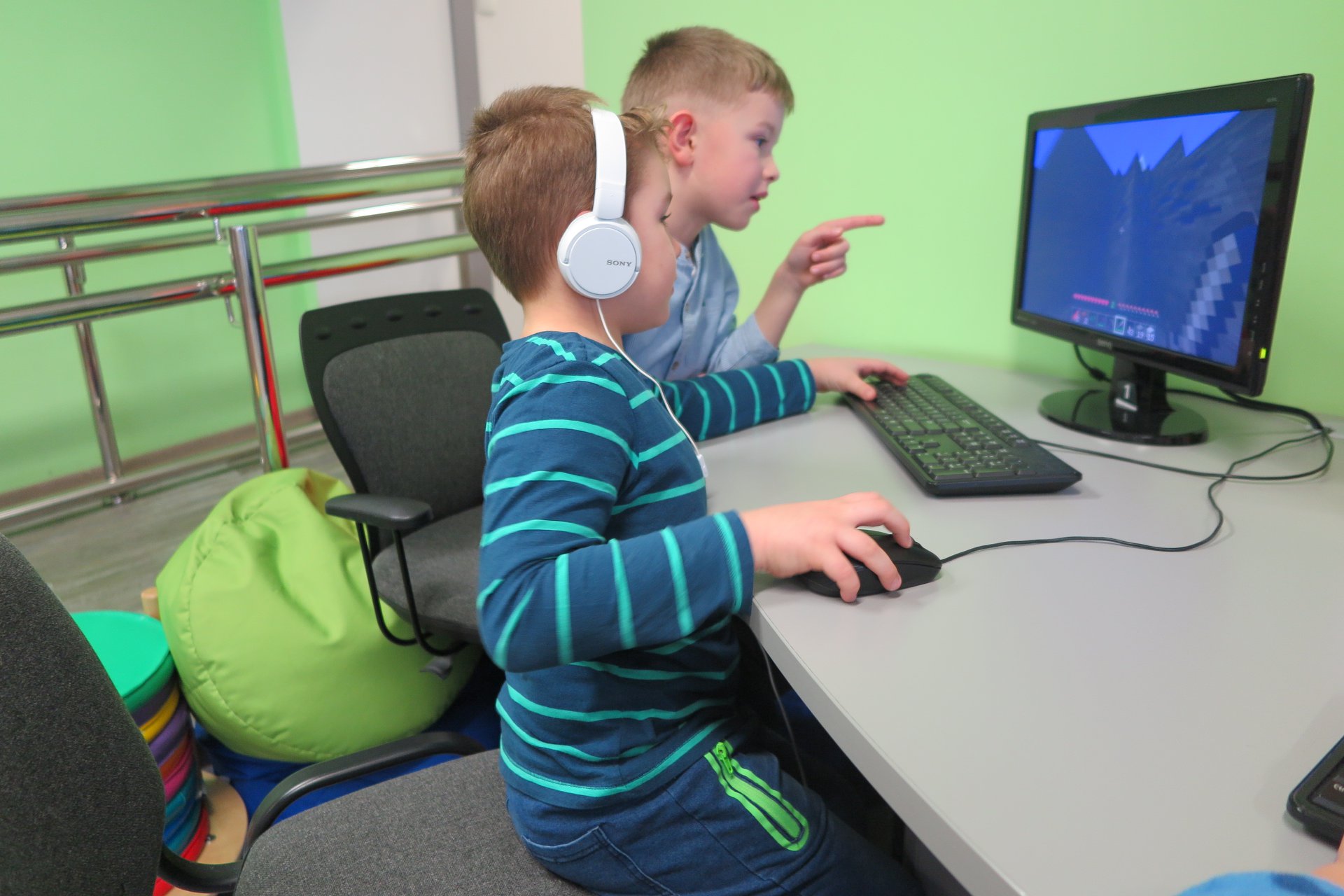 Przy komputerze dwoje chłopców gra w grę.