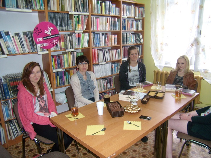 Wnętrze biblioteki, przy stoliku siedzą członkinie DKK ZS Malinowo wspólnie omawiają książkę Antoniny Kozłowskiej "Kukułka".