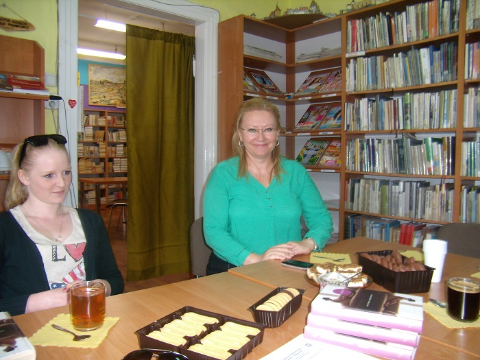 Przy stoliku dyrektor MBP Justyna Lytvyn obok członkini DKK ZS Malinowo, w tle regały z książkami.