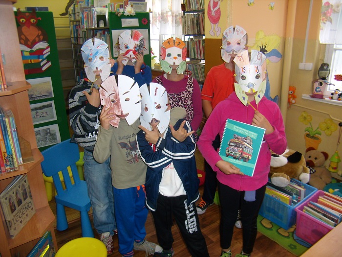 Grupa dzieci w pokolorowanych przez siebie maskach na głowie.