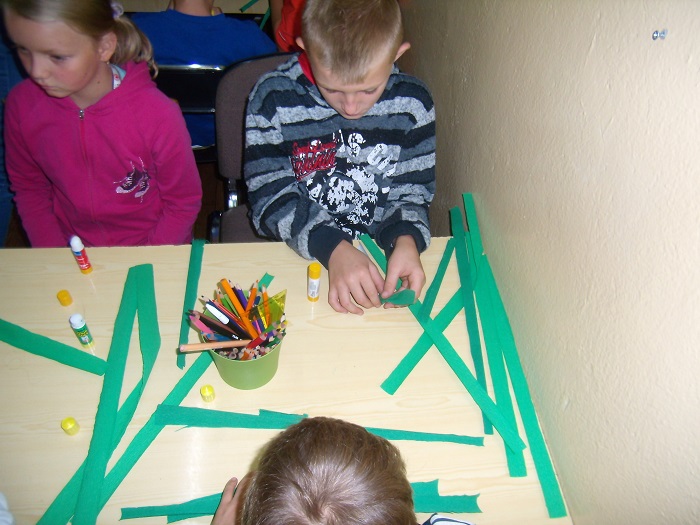 Grupa dzieci wykonuje prace plastyczne w bibliotece.