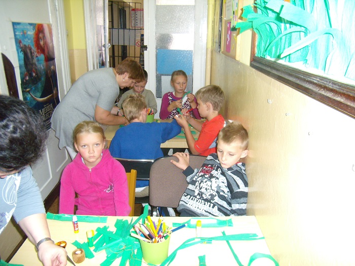 Grupa dzieci wykonuje prace plastyczne w bibliotece.