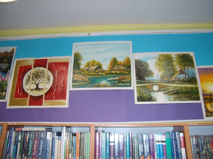Wnętrze biblioteki na ścianie wisi wystawa krajobrazów Lucyny i Jana Mielke.