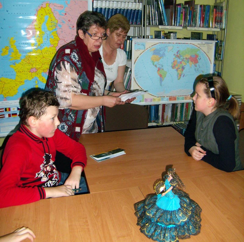Przy stoliku siedzą dzieci zajęcia prowadzi Ewa Sotomska i Marzena Pawłowska w tle wiszą dwie mapy.