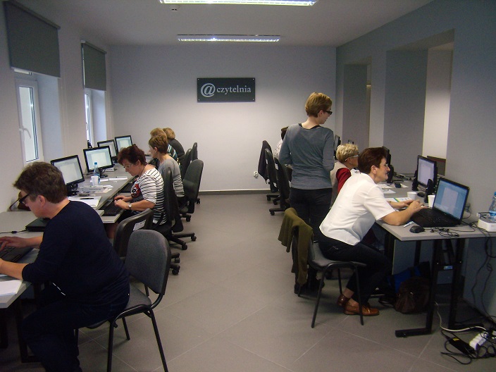 Przy stanowiskach komputerowych uczestnicy kursu komputerowego.