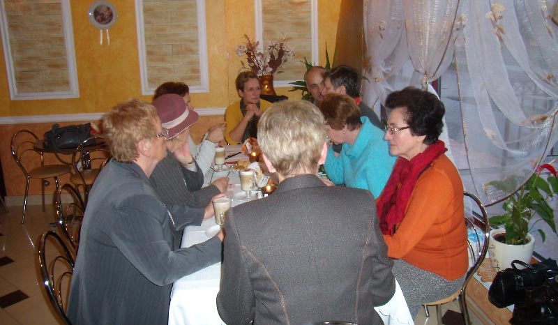 Przy stoliku siedzą członkowie DKK UTW , na stoliku kawa i mały poczęstunek. 