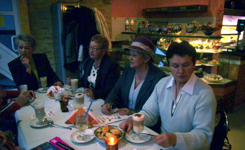 Przy stoliku siedzą członkowie DKK UTW , na stoliku kawa i mały poczęstunek. 