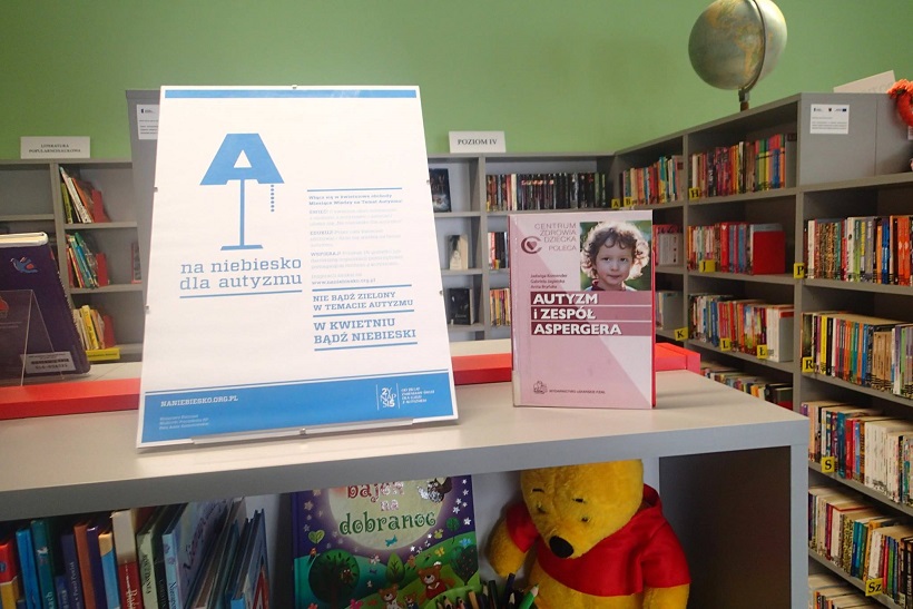 Na regale z książkami stoi plakat pt. Na niebiesko dla autyzmu oraz książka pt. Autyzm i zespół aspergera.