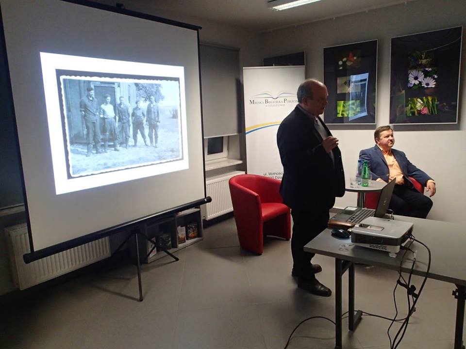 W. Mierzwa i pan M. Gworek opowiadają o swojej nowej książce, obok wyświetlona prezentacja.