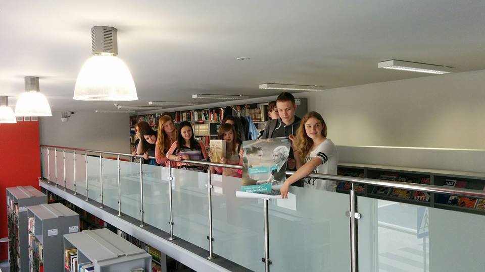 Wnętrze biblioteki, oddział dla dorosłych. Grupa młodzieży bierze udział w lekcji bibliotecznej "O słowie".