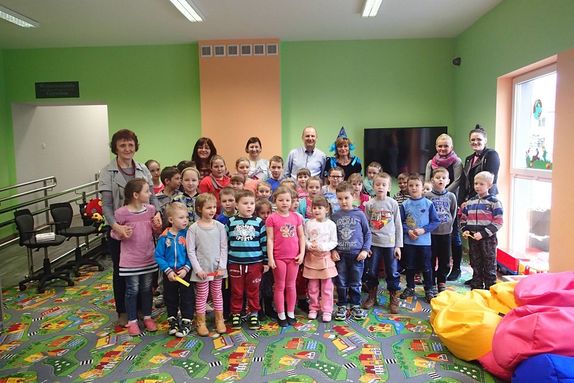 Grupa dzieci siedzi na kolorowych pufach biorą udział w spotkaniu z pisarką Wiolettą Piasecką.