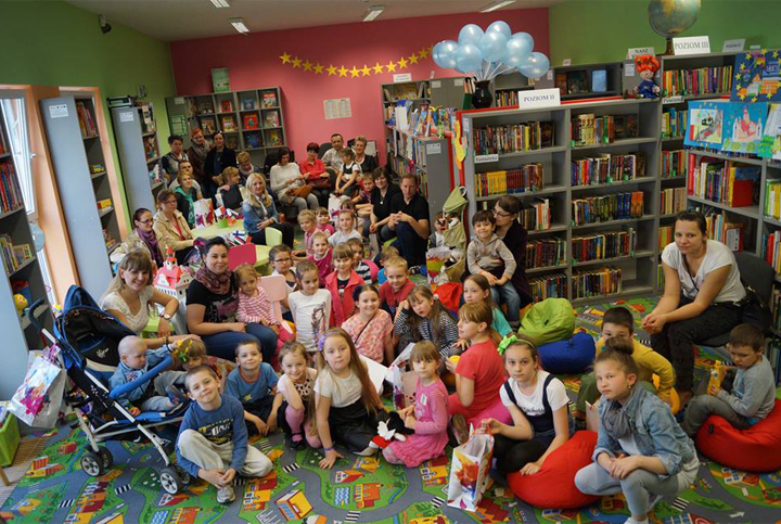 Grupa dzieci z rodzicami podczas dni otwartych funduszy europejskich w bibliotece. 