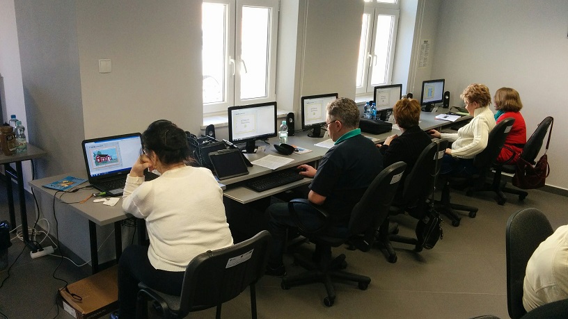 Pięcioro uczestników siedzi przy stanowiskach z komputerami, wszyscy biorą udział w 7 edycji kursu z podstawowej obsługi komputera.