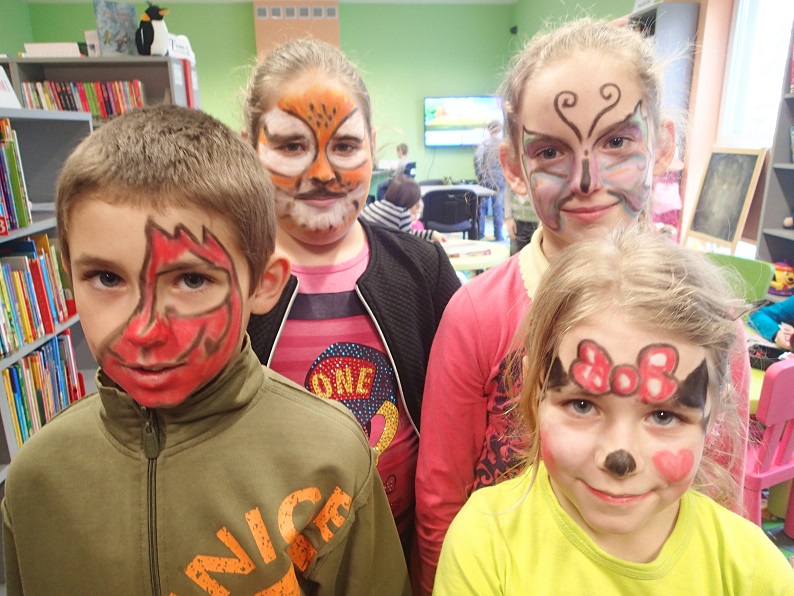 Czworo dzieci z pomalowanymi twarzami w ramach zabawy z makijażem.