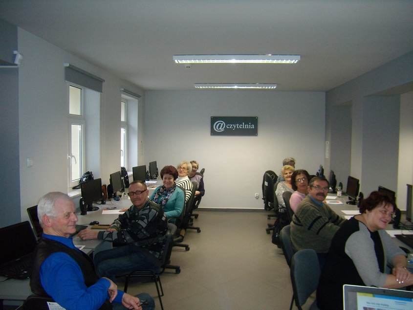 10 uczestników siedzi przy stanowiskach komputerowych, biorą udział w kolejnej edycji kursu komputerowego.