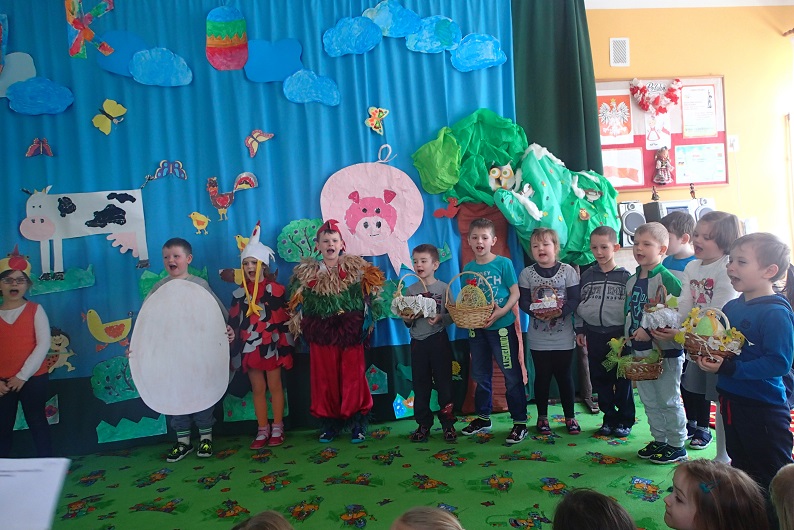 Dekoracja przedstawienia pt. ''Jajko'' dzieci z przedszkola nr 3 wykonały z papieru zwierzątka chmurki, drzewka i udekorowały scene w rękach trzymają koszyki z jajkami.