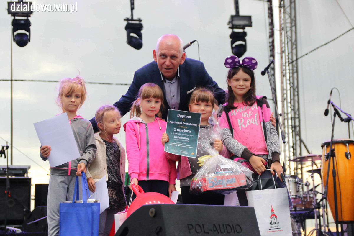 Na scenie stoją dzieci z nagrodami z burmistrzem miasta Działdowo Grzegorzem Mrowińskim.