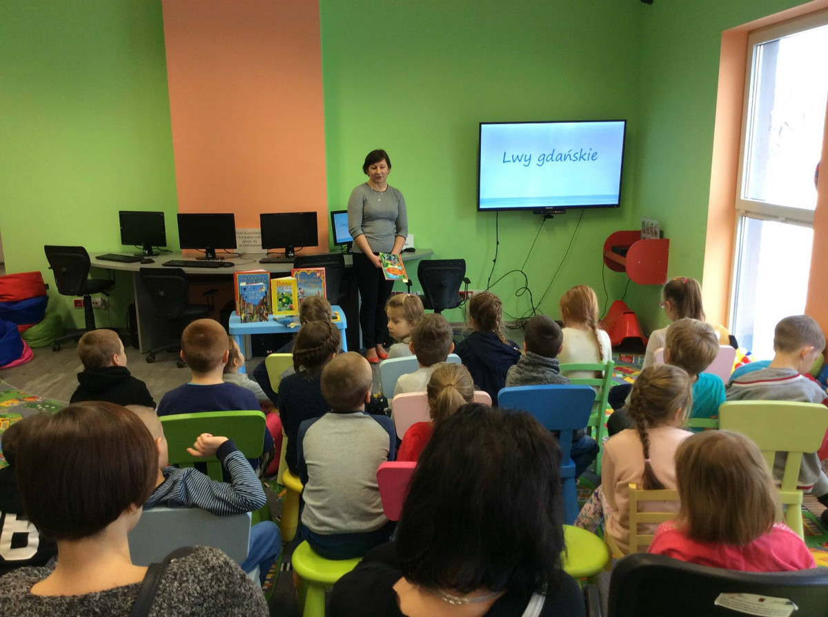 Grupa dzieci ze SP NR 4 wspólnie z bibliotekarką Anią Wiśniewską oglądają prezentację legenda ,,Lwy Gdańskie''.