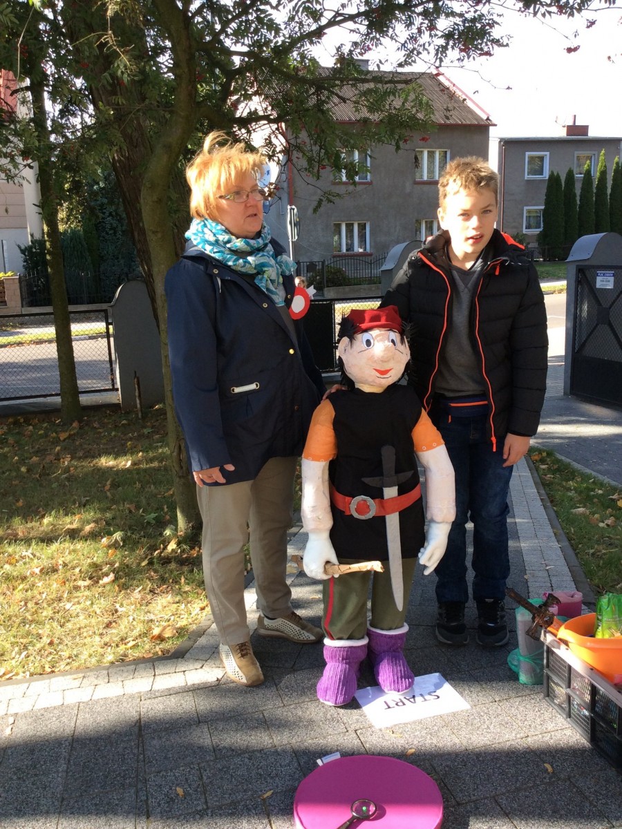 Rodzic z dzieckiem i maskotka postać z bajki na starcie konkursu ''Bajkowy Pionek''. 