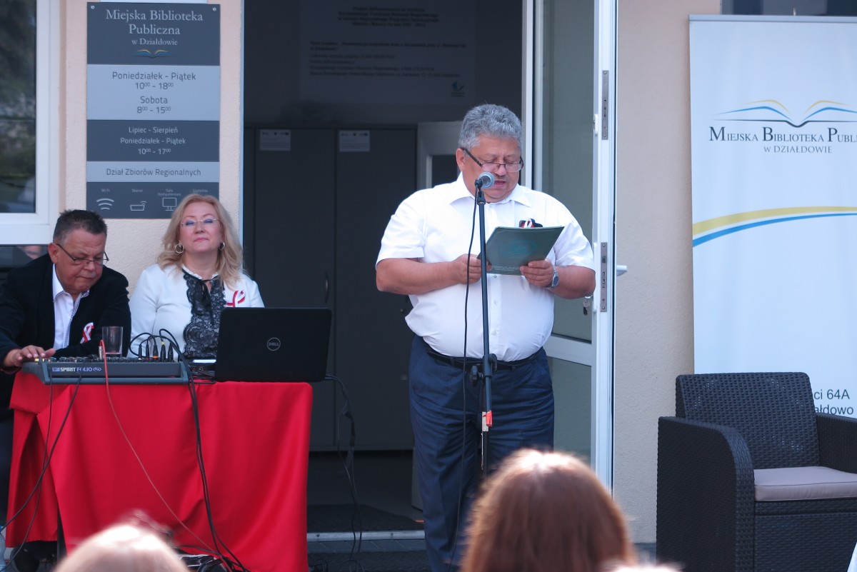 Przy mikrofonie na placu MBP w Działdowie pan Marian Janicki, przy stoliku dyrektor MBP Justyna Lytvyn. 