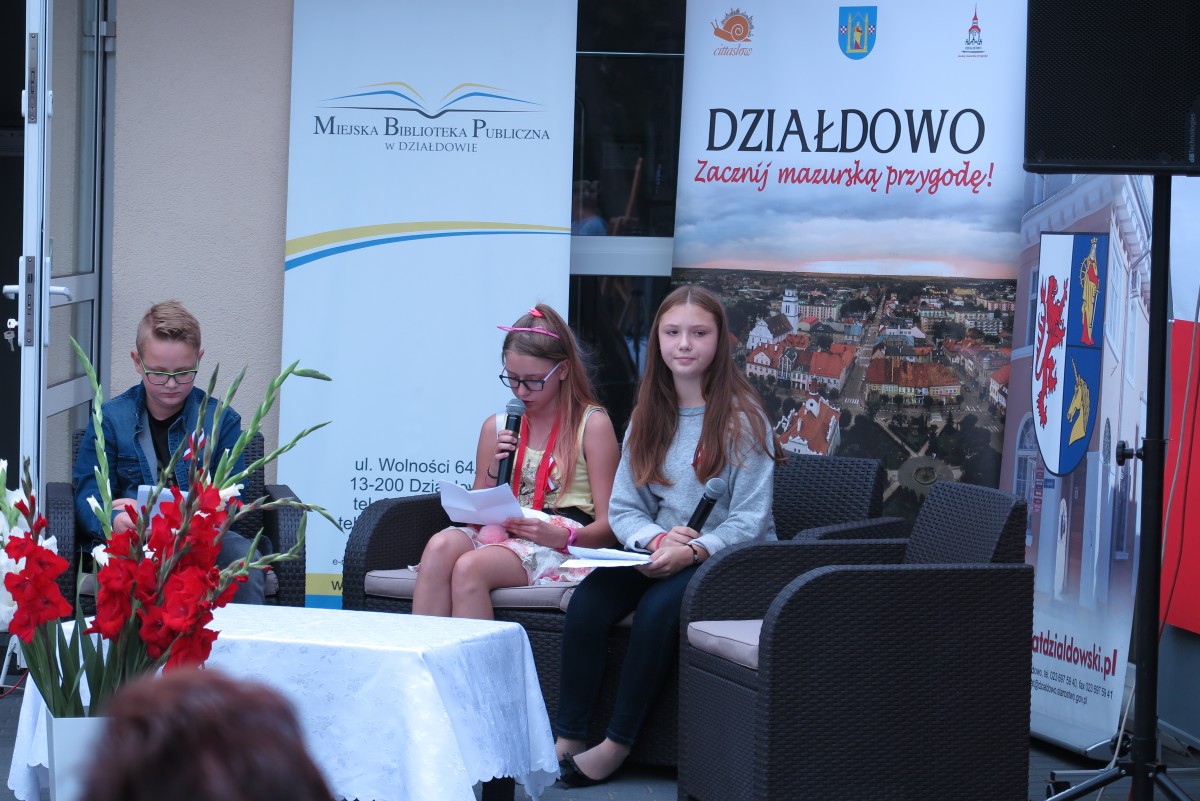 Na kanapie przed MBP w Działdowie z okazji narodowego czytania młodzież czyta powieść ,,Przedwiośnie''.