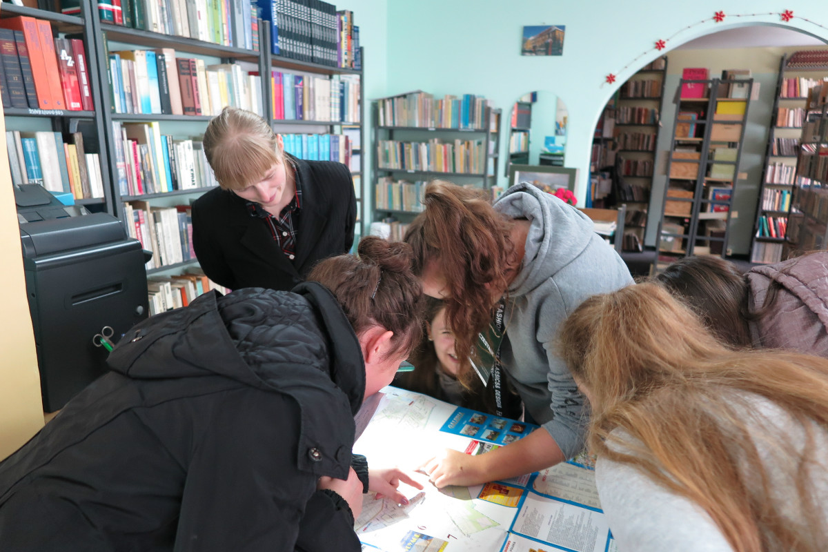 Wnętrze biblioteki w ZS Malinowo, uczestnicy gry miejskiej pt. ''Emilia Sukertowa- Biedrawina- znana i nieznana'' czytają mapę.