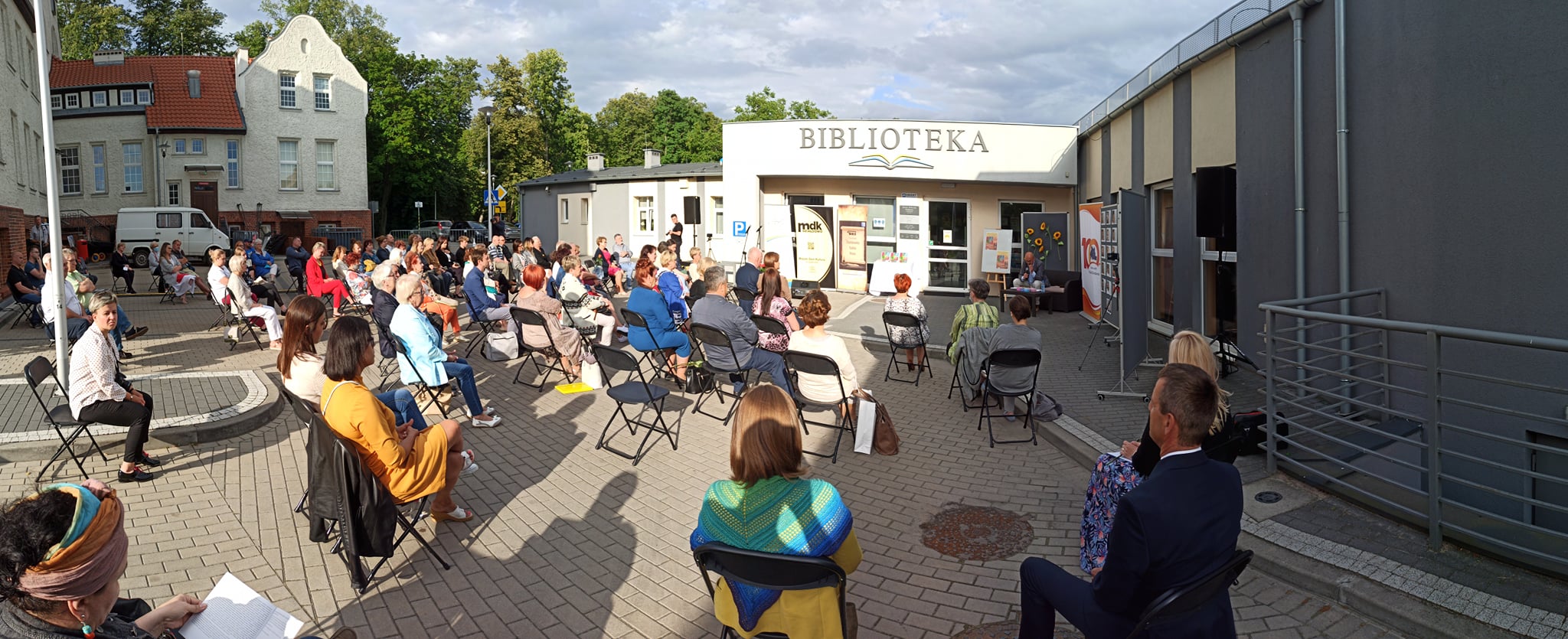 Na placu przed biblioteką w Działdowie przybyli goście którzy zajęli miejsce na krzesełkach by wysłuchać spotkania poezji. Była to promocja publikacji wspomnieniowej ,,7 lat Powiatowych Wieczorów z Poezją. 