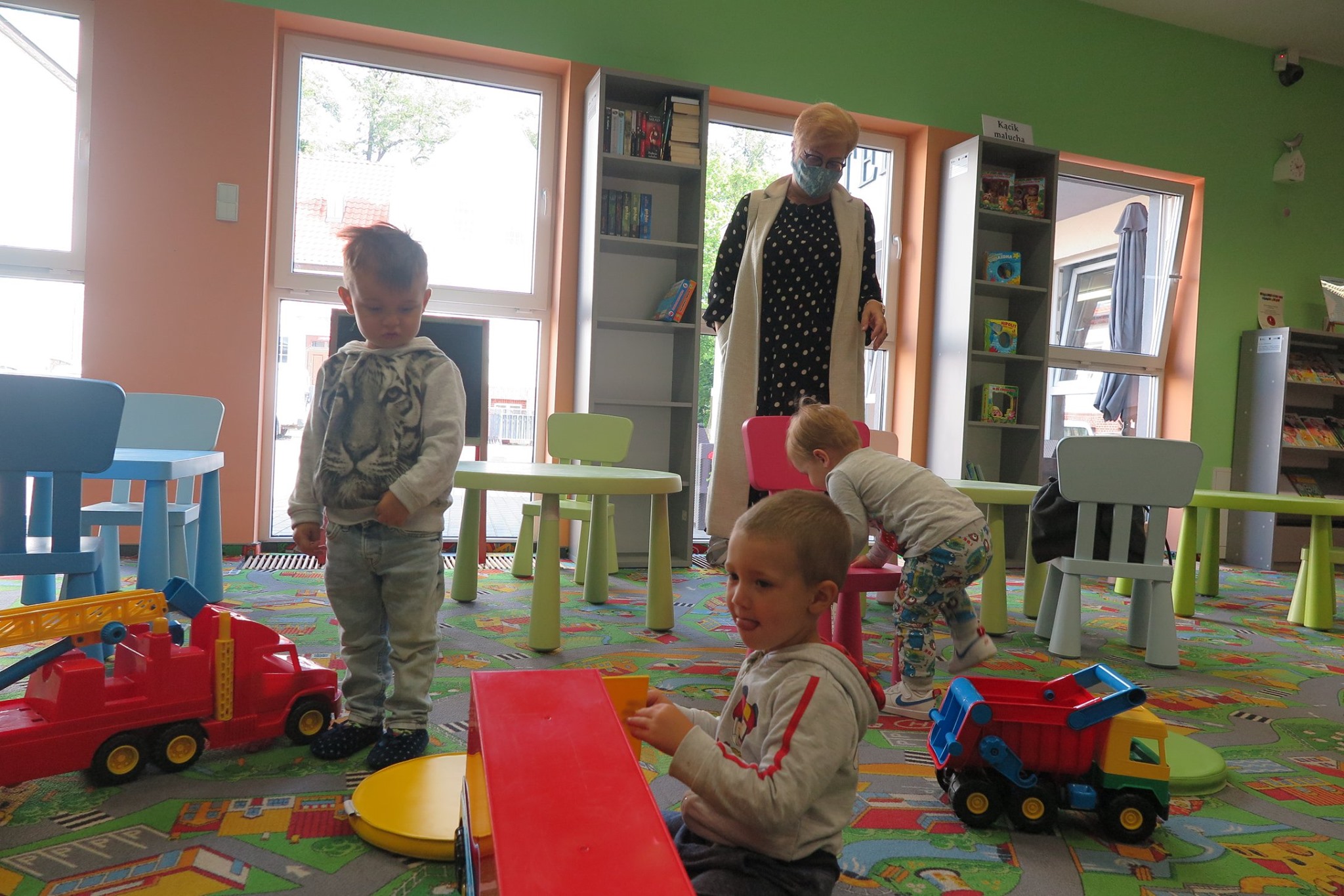 Wnętrze biblioteki (Klub Malucha) troje dzieci bawiące się zabawkami.