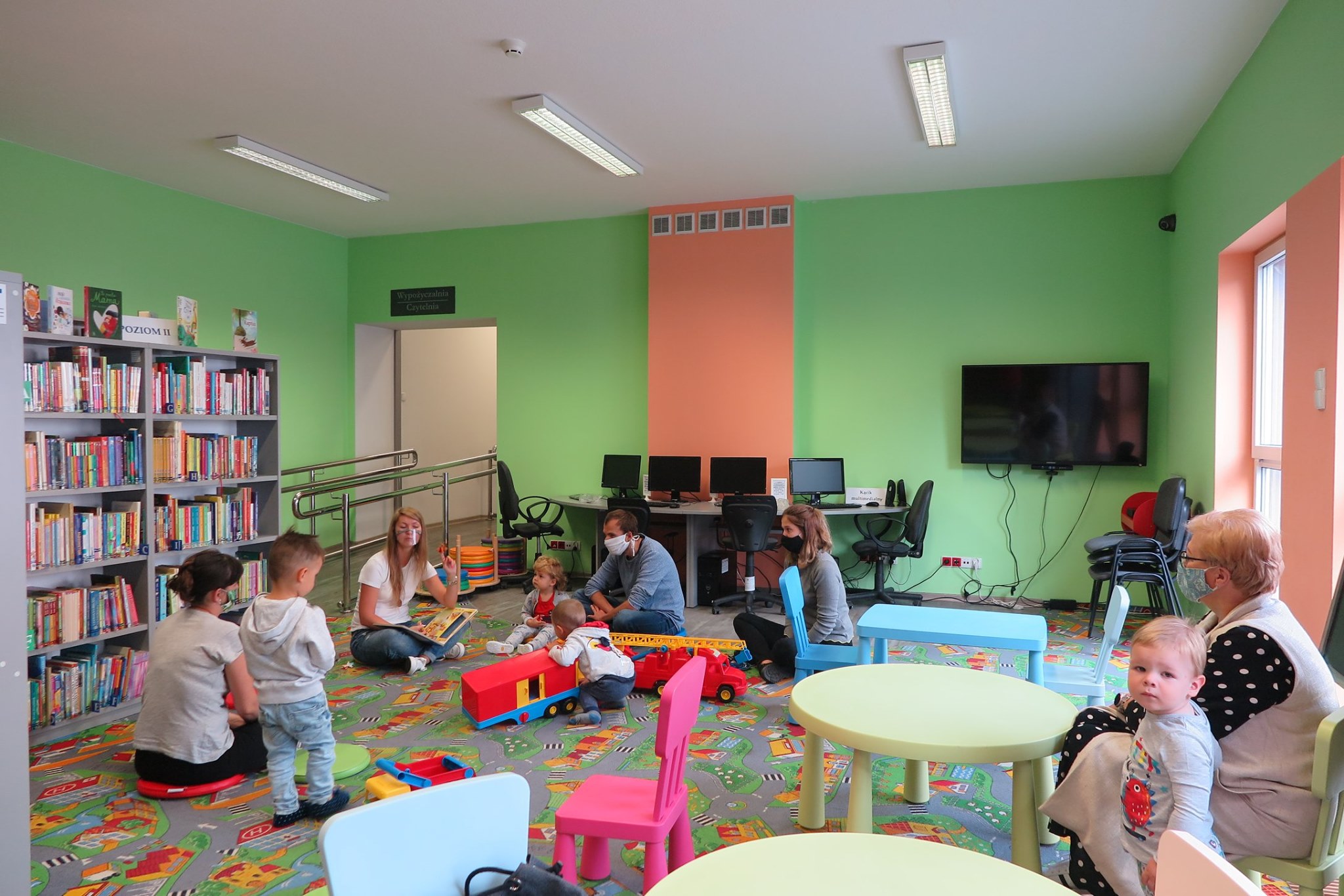 Wnętrze biblioteki (Klub Malucha) dzieci wraz z opiekunami, zajęcia przeprowadza bibliotekarka Aleksandra Cybulska 