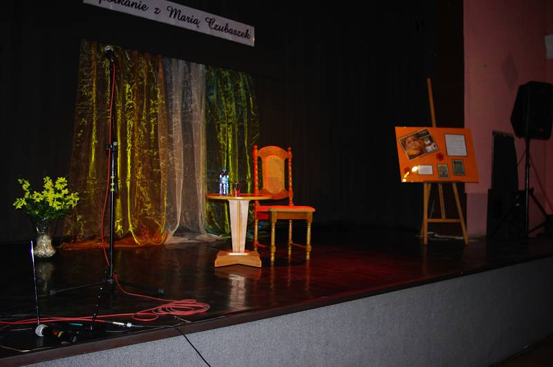 Na scenie stolik krzesło sztaluga z fotografią Marii Czubaszek.