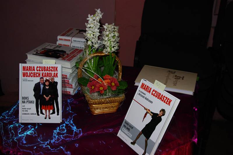 Na stoliku stoi koszyk z kwiatami i książki autorki Marii Czubaszek.