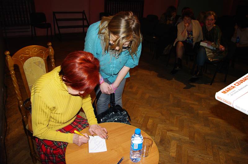 Przy stoliku Maria Czubaszek podpisuje kartkę dla czytelniczki w MDK.