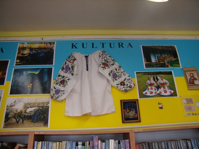 Na ścianie wisi wystawa ''Ukraina- kultura i historia'' , koszula z ozdobnymi rękawami i fotografie Ukrainy.