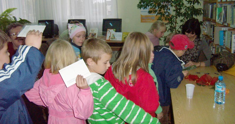 Przy stoliku podpisuje swoją książkę młodemu czytelnikowi Izabella Klebańska za nim kolejka dzieci po autograf.