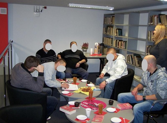 Wnętrze biblioteki, na fotelach siedzą członkowie DKK skazani z aresztu w Działdowie wspólnie omawiają kolejną przeczytaną książkę.