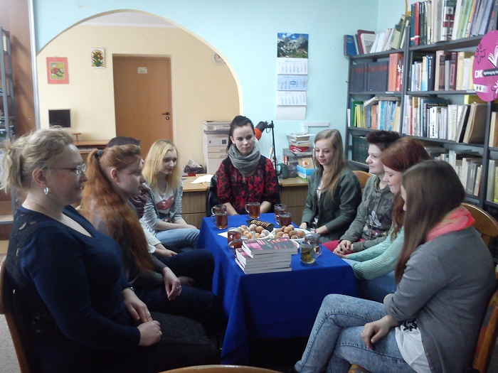 Wnętrze biblioteki, przy stoliku z herbatą i ciastkami siedzą członkinie DKK ZS Malinowo wspólnie omawiają książkę L. Jacobson "Amerykańska gejsza".