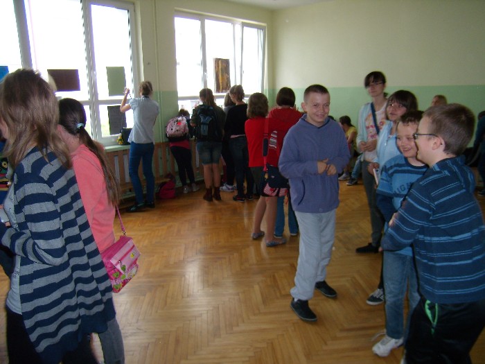 Wnętrze sali gimnastycznej grupa dzieci zbiera się na spotkanie z autorką Beatą Ostrowicką.
