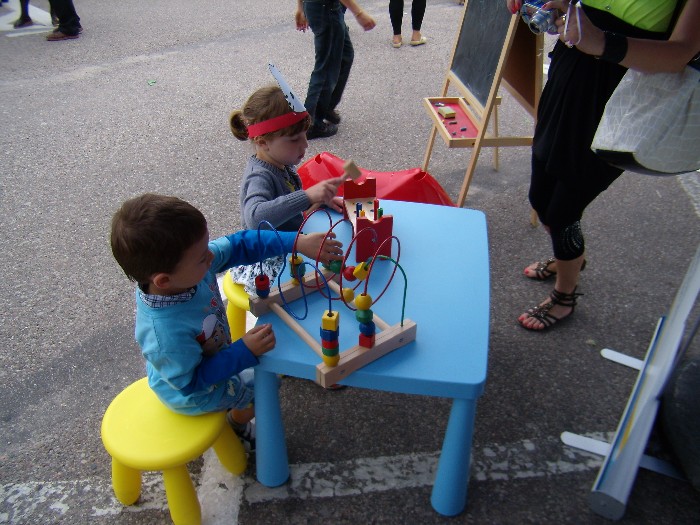 Rynek miasta Działdowa, festyn ''Wstąp po zdrowie'' przy niebieskim stoliku bawią się dzieci zabawkami.