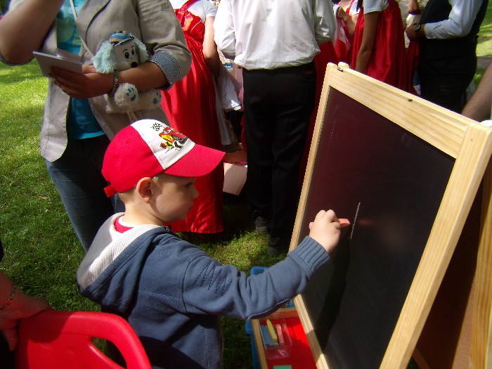 Chłopiec rysuje kolorową kredą na tablicy kredowej.