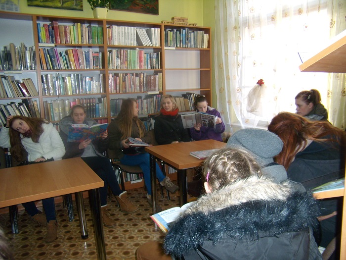 Wnętrze biblioteki, na krzesełkach siedzą uczniowie z Zespołu Szkół Zawodowych w Działdowie biorą udział w lekcji na temat tradycji i zwyczajów świąt Bożego Narodzenia.